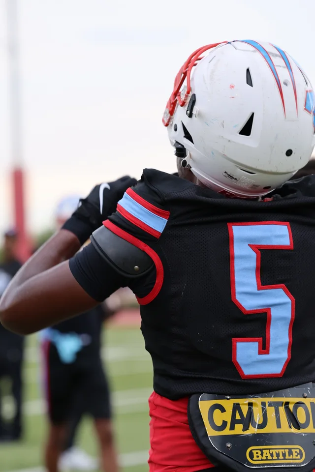 A Madison player seen from behind in a white helmet and black number 5 jersey.
